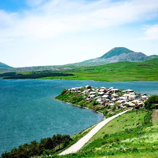 Живописная дорога вдоль ярко-бирюзового озера Табацкури среди зеленых холмов