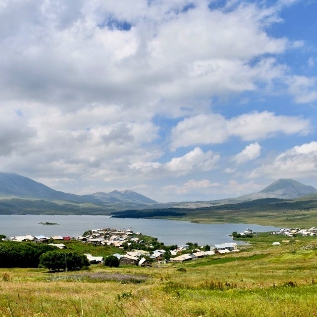 Панорамный вид на высокогорное село Табацкури на берегу синего озера в Грузии